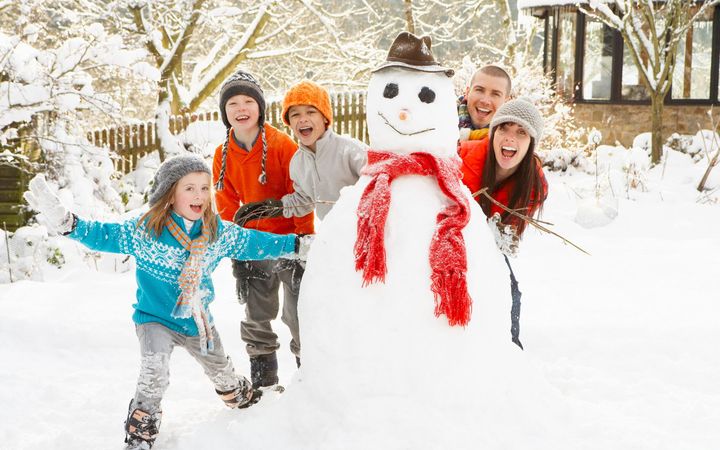 Une famille sculpte un bonhomme de neige