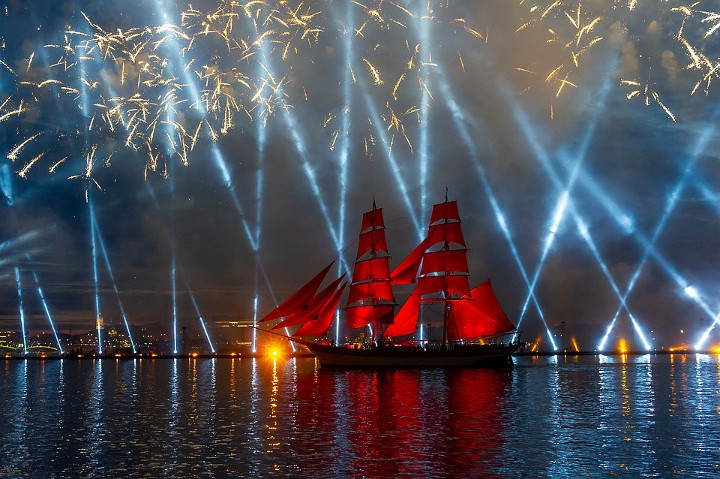 loď s červenými plachtami na pozadí laserové show